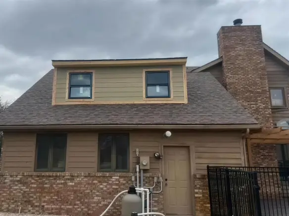 Zach's finished room addition: a sided dormer with new black windows.