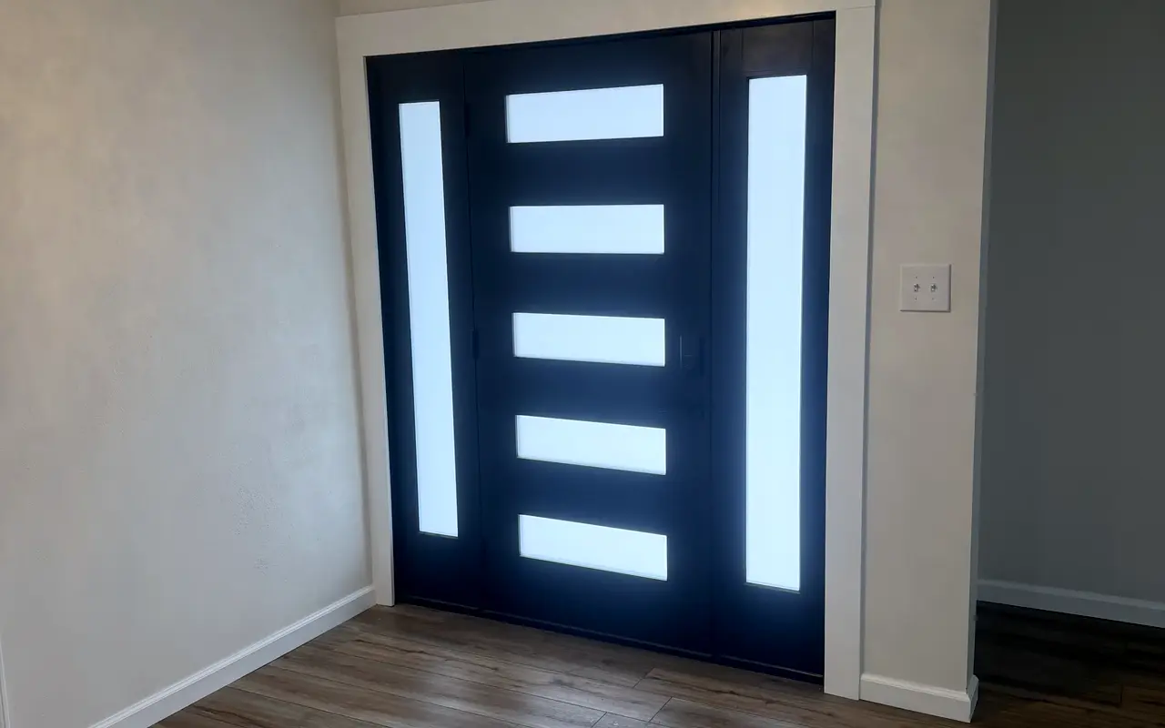 A modern black front door with glass panels, over new wood floors.