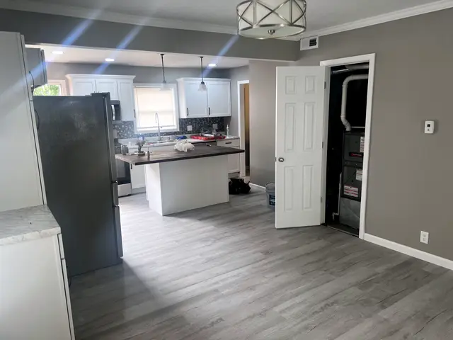 A remodeled kitchen with white cabinets, stainless appliances and a large island.